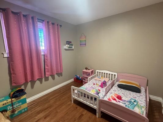 Children's bedroom with pink curtains and beds.
