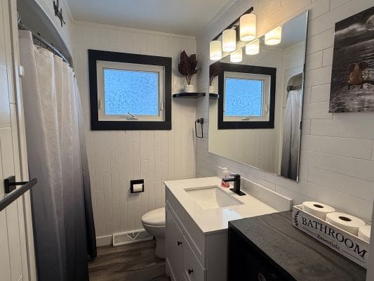 Modern bathroom with white fixtures and decor.
