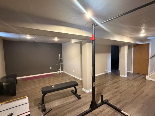 Home gym with weights and bench.