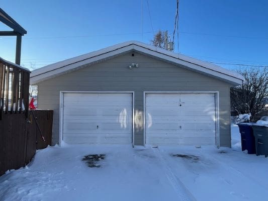 Snow-covered garage with two white doors.