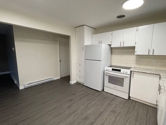 Small kitchen with white appliances and cabinets.