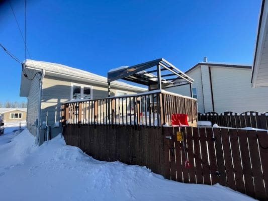 Snow-covered backyard with wooden deck and fence.