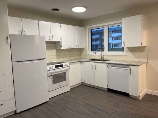 Modern kitchen with white cabinets and appliances.