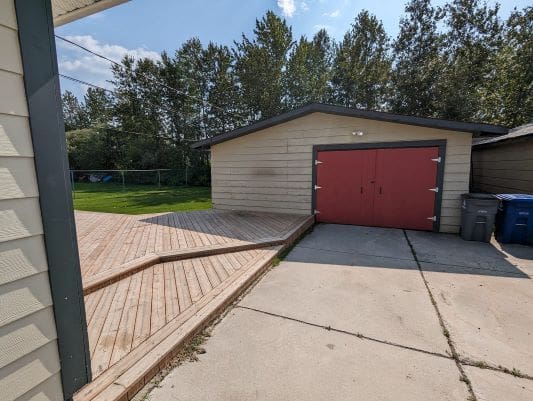 Garage with red doors and wooden deck.