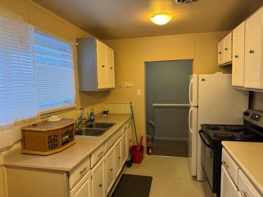 Compact kitchen with white cabinets and appliances.
