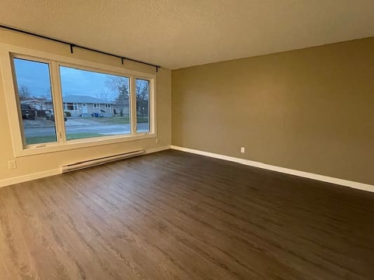 Empty room with large window and flooring.