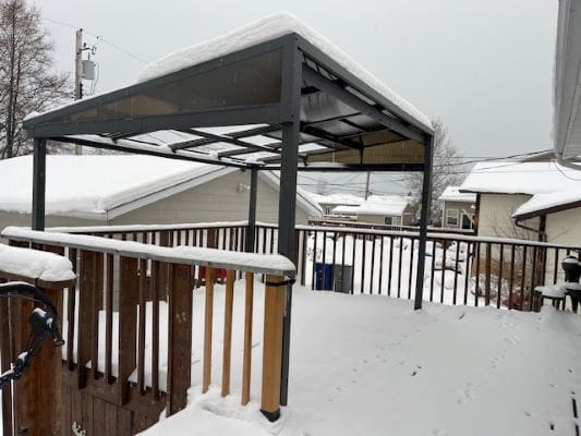 Snow-covered deck with metal pergola structure.