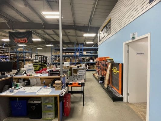 Warehouse interior with desks and storage shelves.