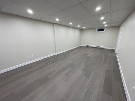 Unfurnished basement with wooden flooring and lights.
