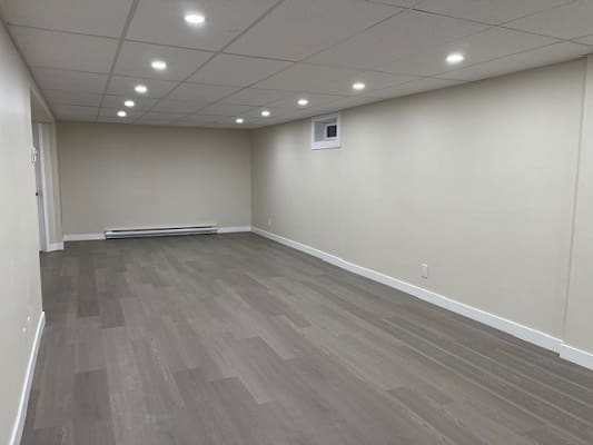 Empty basement with wood flooring and lights.