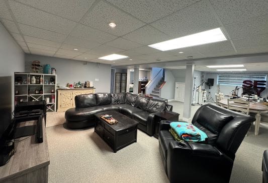Spacious basement with leather furniture and gym.