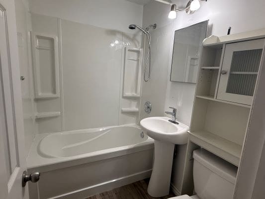 Small white bathroom with bathtub and sink.