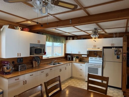 Wooden kitchen with white cabinets and appliances.