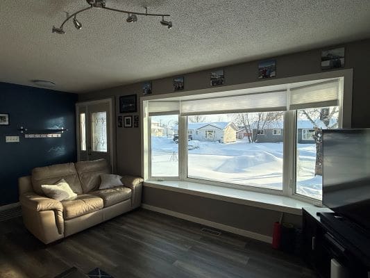 Living room with large window, snowy view.
