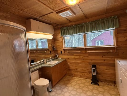 Wood-paneled bathroom with shower and sink.