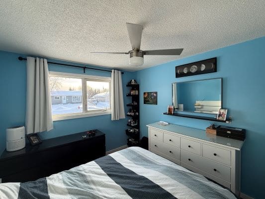 Blue bedroom with window and dresser.