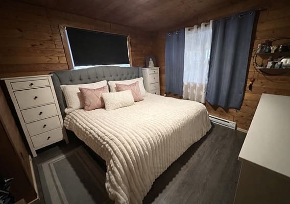 Cozy bedroom with wooden walls and bed.