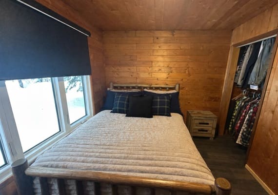 Cozy bedroom with wooden walls and bed.