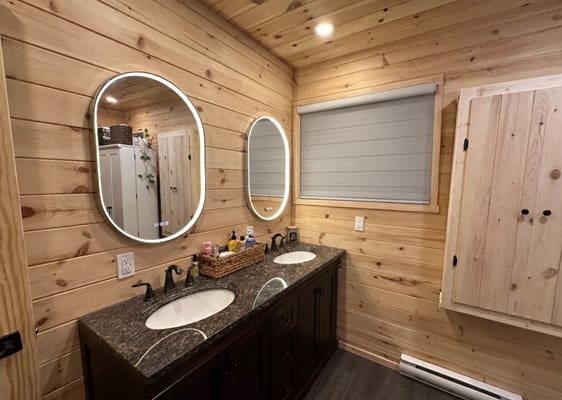 Wood-paneled bathroom with double sinks and mirrors.