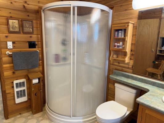 Wood-paneled bathroom with a corner shower.