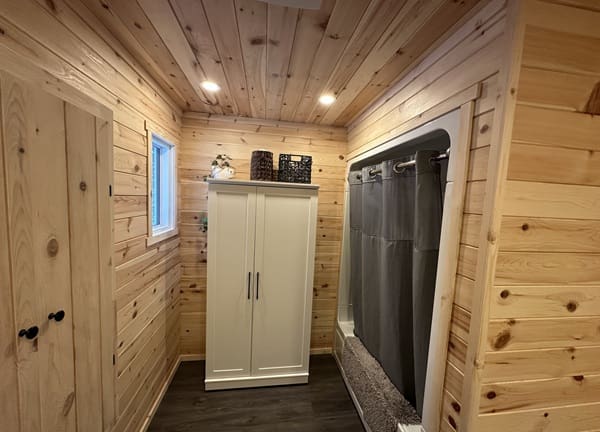 Wood-paneled bathroom with white wardrobe and shower.