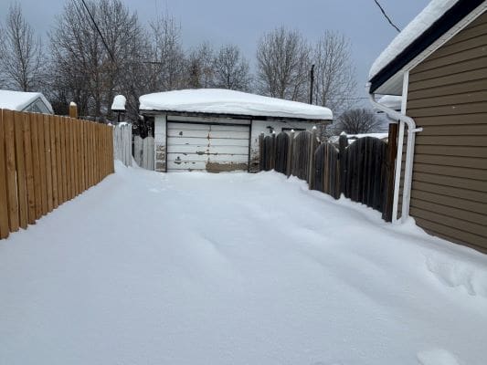 Snow-covered driveway and garage in winter.