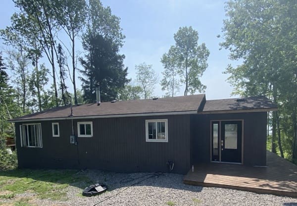 Small brown house surrounded by trees.
