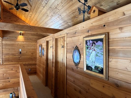 Wooden hallway with framed paintings on walls.
