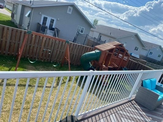 Backyard with playset and white railing deck.