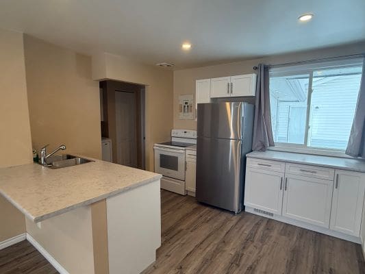 Modern kitchen with white cabinets and appliances.