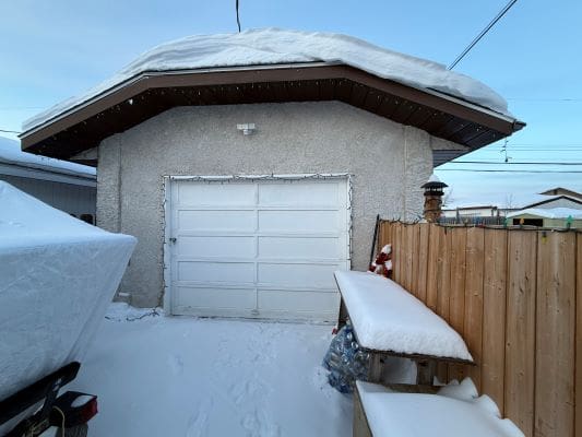 Snow-covered garage and wooden fence in winter.