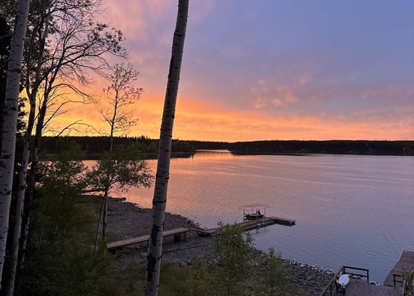 Sunset over a tranquil lakeside scene.