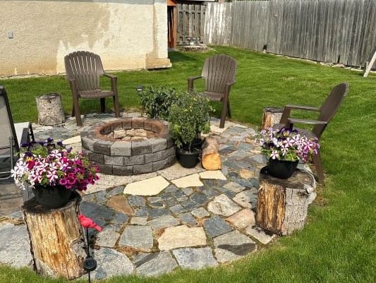 Backyard patio with fire pit and chairs.