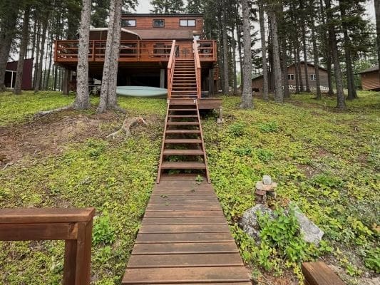 Wooden cabin with stairs in forest setting.