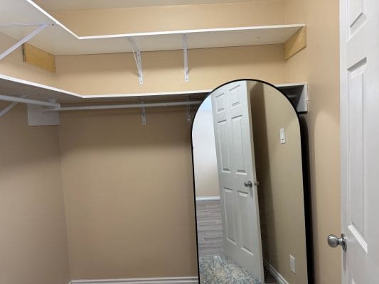 Empty closet with mirror and shelves.