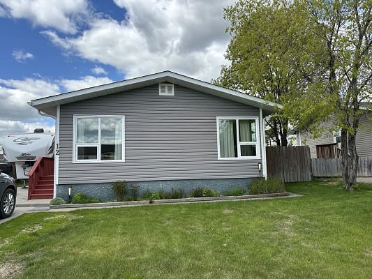 Gray house with lawn and cloudy sky.