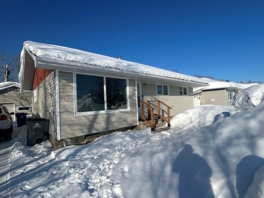Snow-covered house under clear blue sky.