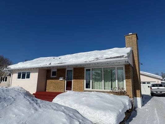 House covered in snow under clear sky.