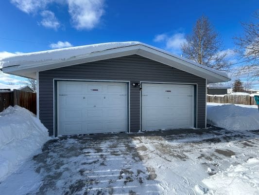 Snow-covered garage with two white doors.