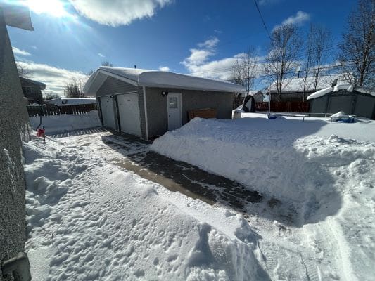 Snow-covered driveway leading to a garage.