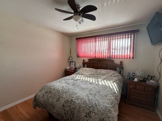 Bedroom with fan and large window blinds.