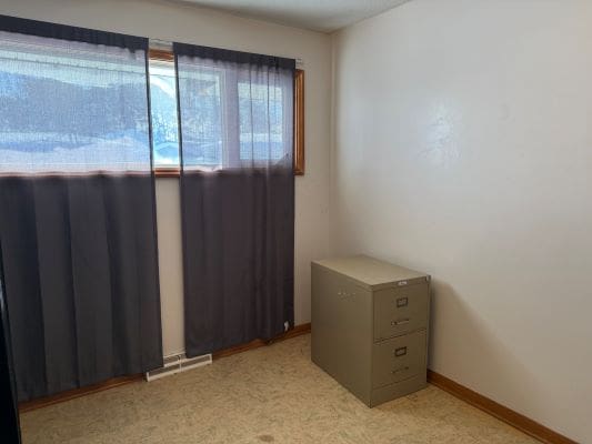 Empty room with curtains and filing cabinet.