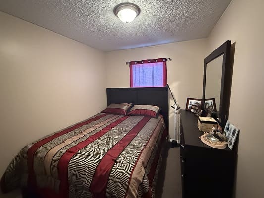 Small bedroom with bed and dresser.