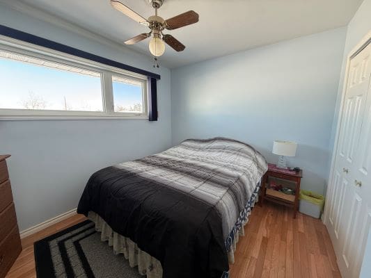 Bedroom with bed, ceiling fan, and window.