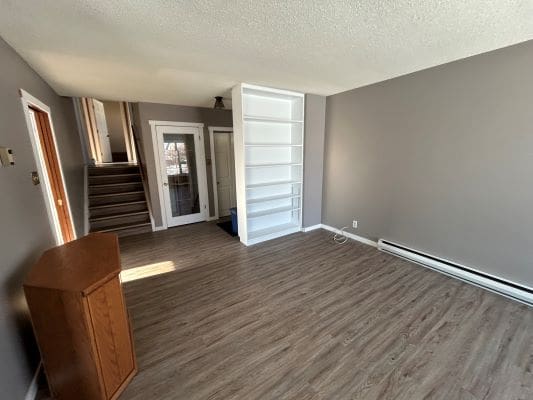 Empty room with staircase and wooden floor.