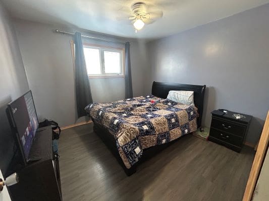 Bedroom with bed, TV, and nightstand.
