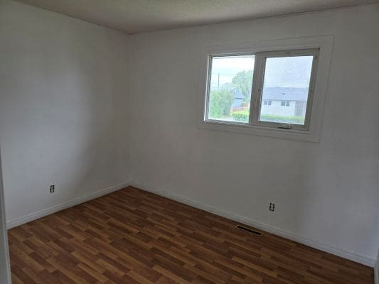Empty room with wooden flooring and window.