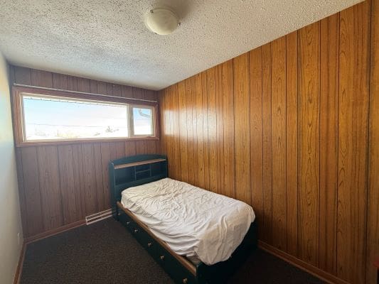Small bedroom with wood-paneled walls.