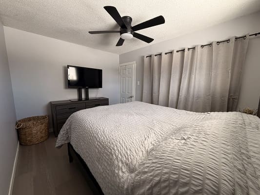 Modern bedroom with bed, TV, and curtains.