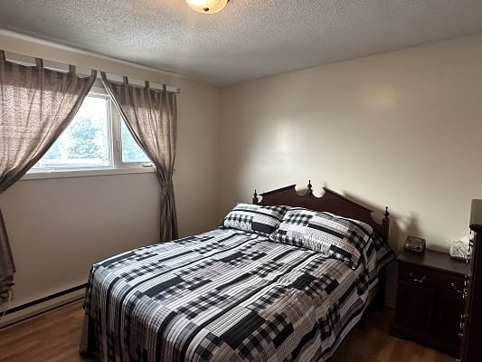 Bedroom with bed, window, and curtains.